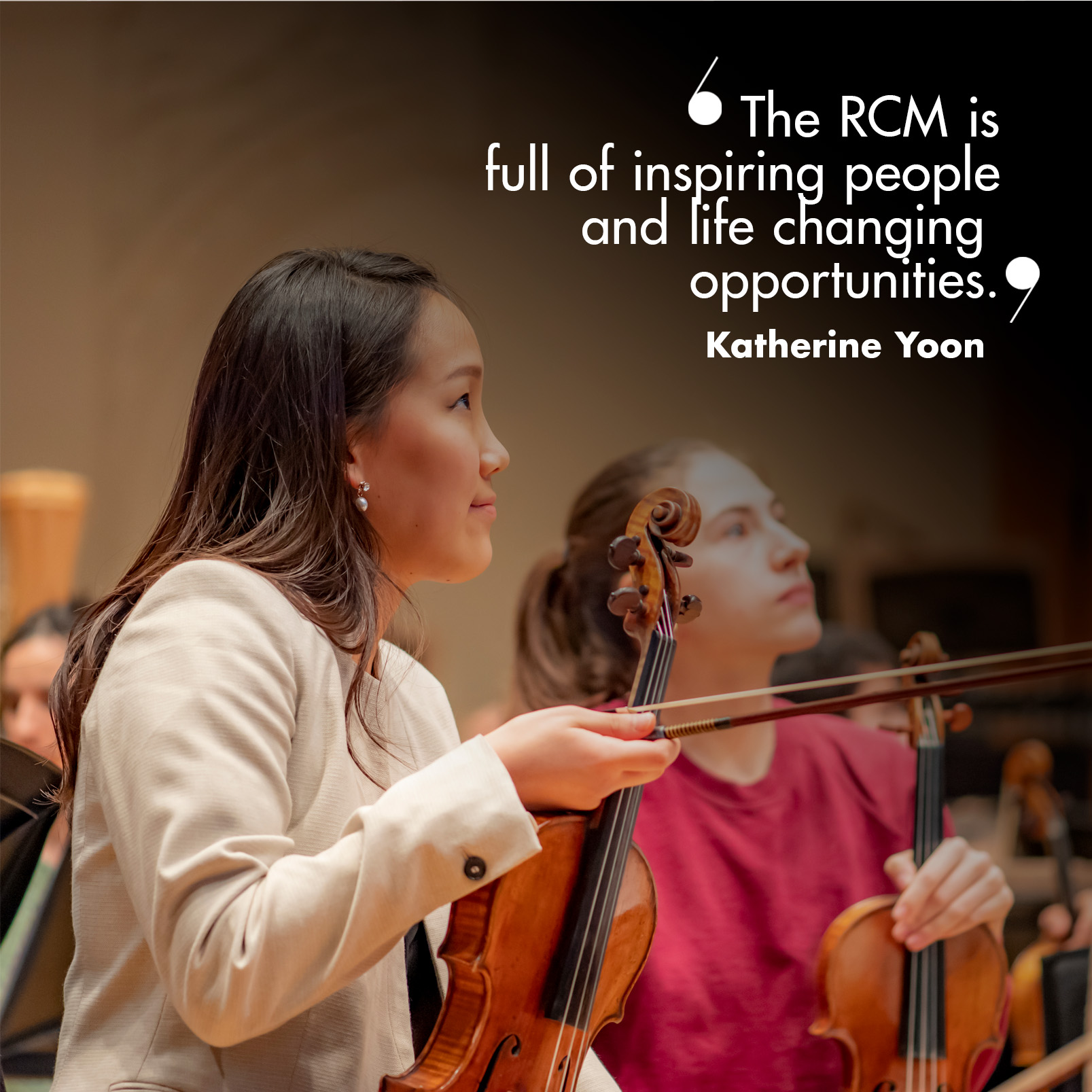 “The RCM is an incredible place, full of inspiring people and life changing opportunities". A female student, wearing a white jacket, sitting in an orchestral rehearsal, holding her bow and violin.